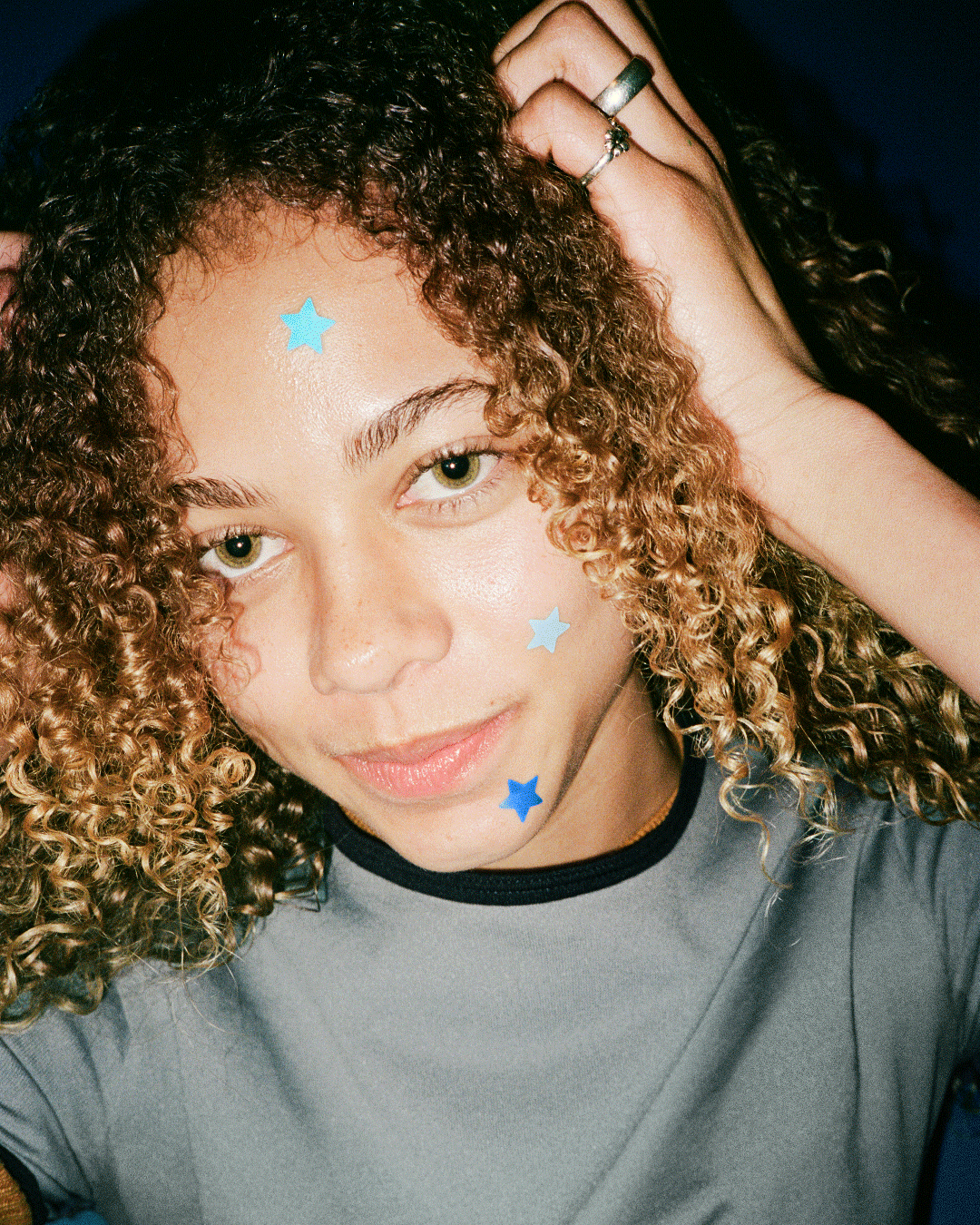 A person wearing blue Starface Hydro-Star® + Salicylic Acid patches. Star-shaped patches that shrink spots.