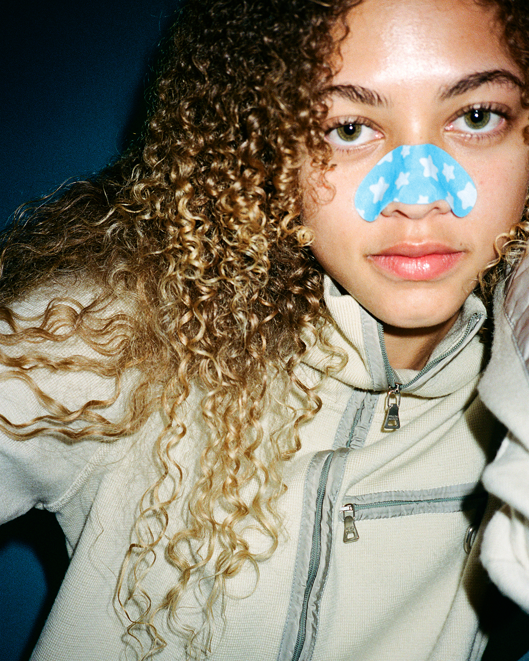 A person wearing a blue Starface Star Strips™ + Salicylic Acid on their nose. Pore strips that remove blackheads.